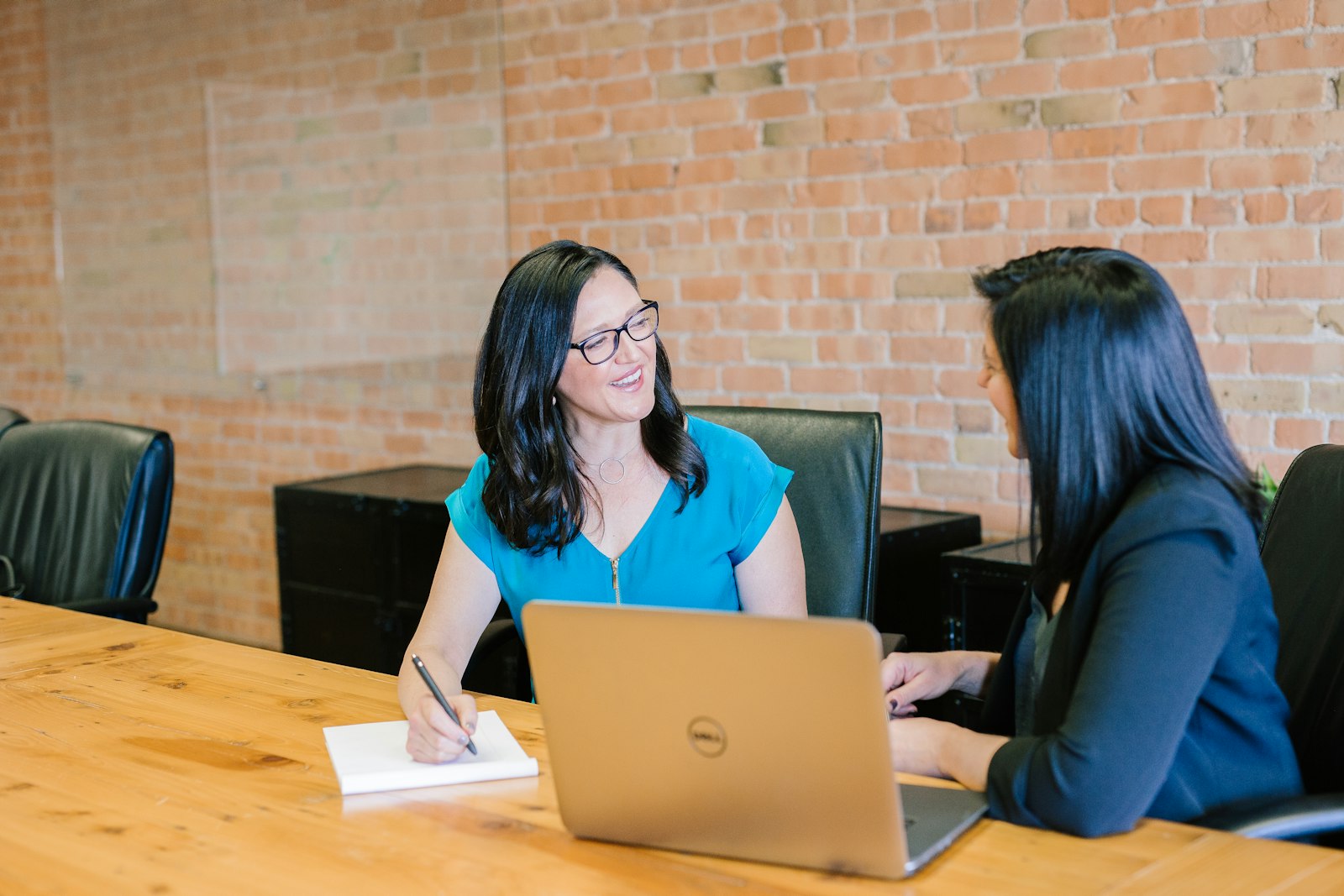 Two colleagues talking across a table with a laptop open