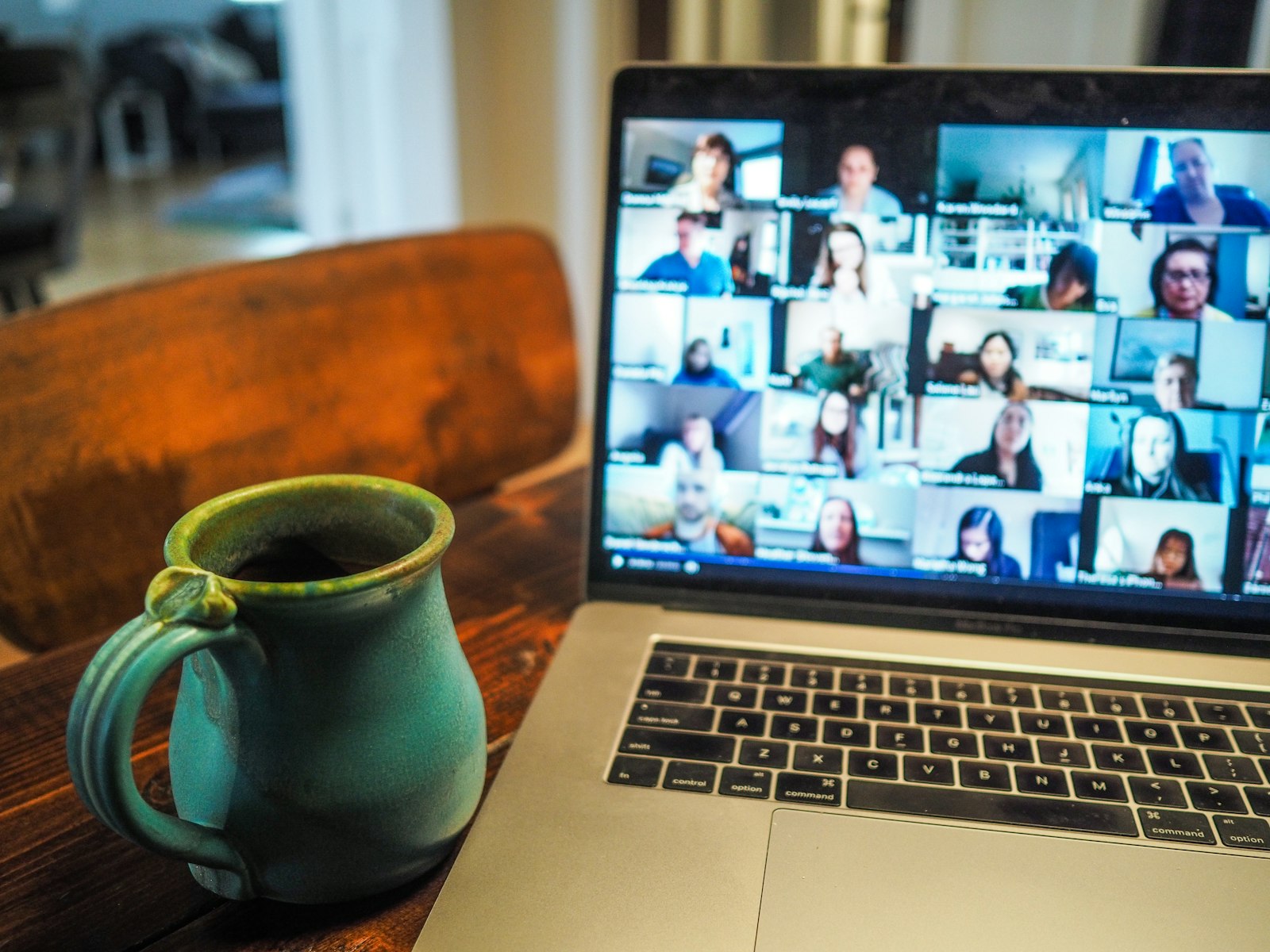 A laptop showing a video call with many participants, next to a coffee mug